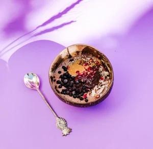 Smoothie bowl with berries, chia seeds and peanut butter in a coconut shell